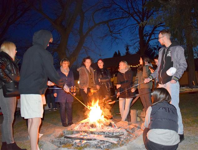 Wychowawcy, Pani Dyrektor i młodzież stoją wokół ogniska i pieką kiełbaski.