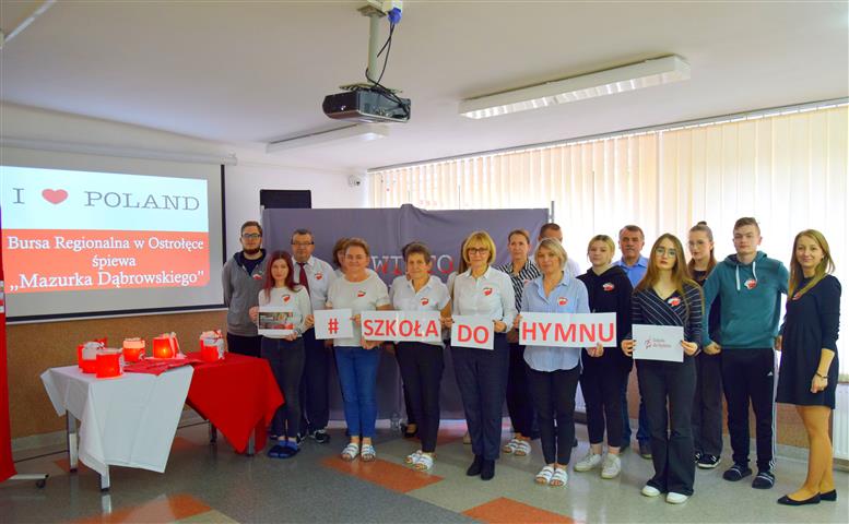 Wychowankowie oraz kadra placówki pozują na tle dekoracji podczas udziału w akcji "Szkoła do hymnu"