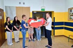 Wychowankowie SOSW trzymają przekazane im wielkie papierowe, czerwone serce wypełnionekkartami z życzeniami