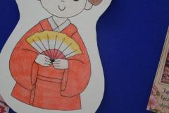 Zdjęcie przedstawia rysunek Japonki ubranej w tradycyjne kimono, trzymającej wachlarz, nawiązujący do kultury Japonii.