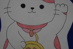 Zdjęcie przedstawia rysunek Maneki-neko („wzywającego kota”) – tradycyjnej japońskiej figurki przedstawiającej siedzącego kota z uniesioną łapą, nawiązującej do kultury Japonii.