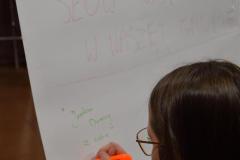 Wychowanka podczas zajęć edukacyjnych wpisuje na tablicy – słowa wsparcia dla grupy wychowawczej.