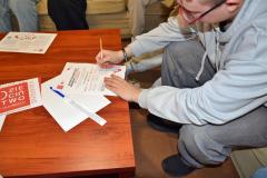 Wychowanek podpisuje Manifest kampanii „Dzieciństwo bez przemocy” , obok znajdują się materiały informacyjne i logo akcji.