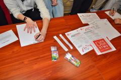 Grupa wychowanków bursy podczas zajęć. Na stole znajdują się materiały informacyjne.