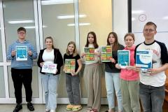 Grupa wychowanków bursy stoi w sali, trzymając plakaty i ulotki edukacyjne.