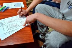 Wychowanek wypełnia kartę pracy, obok znajdują się materiały informacyjne