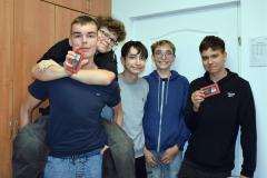 Pięcioro uśmiechniętych wychowanków pozuje na tle ściany. Dwoje z nich trzyma w ręku czekoladkę wręczoną z okazji Dnia Chłopaka.