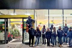 Młodzież stojąca przed wejściem do supermarketu