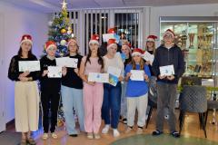 Grupa wolontariuszy z wychowawcą prezentują wykonane przez siebie kartki świąteczne