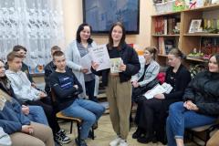 Wychowanka odbiera nagrodę i dyplom za zajęcie I miejsca. Wokół pozostali uczestnicy konkursu