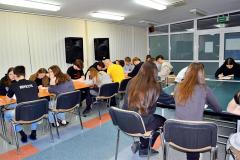 Wychowankowie bursy siedzą przy stole, pochyleni nad pytaniami konkursowymi zorganizowanego z okazji Międzynarodowego Dnia Języka Ojczystego.