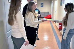 Grupa uśmiechniętych wychowanków wręcza koleżance ulotkę promującą akcję: „Międzynarodowy Dzień Praw Dziecka z UNICEF”.