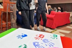 Młodzież uczesnicząca w zajęciach "Empatyczna klasa" swoje dłonie farbowane róż ymi kolorami na białej karcie