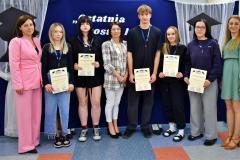 Wychowankowie, wychowawcy i Pani Dyrektor pozują do zdjęcia. Młodzież w rękach trzyma dyplom z podziękowaniem za pracę na rzecz bursy.