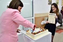 Pani Dyrektor kroi tort. Obok stoi wychowanka z dyplomem w ręku.