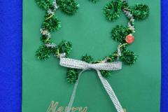 Kartka świąteczna z napisem Merry Christmas, z zielonym wieńcem z białą kokardą, na zielonym tle.