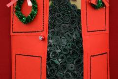 Kartka świąteczna: Czerwona kartka w kształcie drzwi, które się otwierają na boki. Na drzwiach wiszą zielony wieniec z czerwoną kokarda i czerwona kokarda z zieloną bombką. W środku drzwi znajduje się na żółtym tle: zielona choinka ze zwiniętych w kółeczka kartek papieru, na czubku choinki znajduje się żółta kokardka. Pod kartką znajduje się napis: Wyróżnienie: Głażewska Sandra – Internat przy ZSZ nr 2 w Ostrołęce