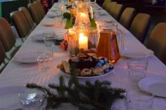 Sala w  której  na pierwszym planie znajduje się jeden długi stół z krzesłami: przykryty białym obrusem. Na stole znajdują się świece w szklanych wazonach, gałązki świerku, talerze, szklanki, dzbanki z wodą i sokami. Na talerzach znajdują się  ciastka. Po lewej stronie znajduje się czerwona tablica na której znajdują prace konkursowe (kartki świąteczne). Z boku stoi stolik  z nagrodami. Z tyłu stoi niebieska tablica z białymi gwiazdkami. Na tablicy wiszą zapalone lampki. Przed tablicą stoi stół przykryty białymi obrusami.  Na stole znajdują się dekoracje świąteczne: lamki, choinka, gałązki świerku. W sali panuje świąteczna i nastrojowa atmosfera. 