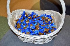 Wiklinowy kosz z czekoladkami w kształcę sztabek złota z niebieską kokardą