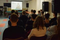 Młodzież siedząca na krzesłach oraz Pani dietetyk przedstawiająca informacje