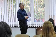 Policjant tłumaczy młodzieży zasady bezpieczeństwa w ruchu drogowym.