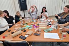 Wychowanki siedzą przy stole i mierzą sznurek jutowy