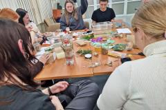 Wychowankowie siedzą przy stole z materiałami do pracy