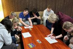 Grupa wychowanków bursy podczas zajęć. Na stole znajdują się materiały informacyjne.