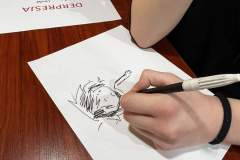 Wychowanka wypełnia kartę pracy, obok znajdują się materiały informacyjne.