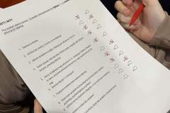 Wychowanka wypełnia kartę pracy, obok znajdują się materiały informacyjne.