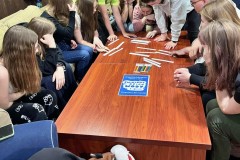 Grupa wychowanków bierze udział w zajęciach edukacyjnych na temat Światowego Dnia Wody. Wspólnie rozwiązują zadanie, używając pasków papieru i flamastrów.