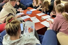 Wychowankowie obliczają, ile wirtualnej wody kryje się w codziennym śniadaniu. Na stole widoczne są materiały edukacyjne.
