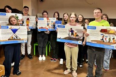 Wychowankowie prezentują plakaty Polskiej Akcji Humanitarnej z kodami QR.