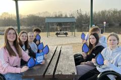 Grupa młodzieży siedzi w altance. Wychowankowie w rękach trzymają materiały informacyjne.