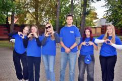 Członkowie Młodzieżowej Rady Bursy w niebieskich koszulkach pozują uśmiechnięci.