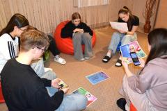 Grupa młodzieży uczestniczy w akcji „W pełnym wymiarze”. Scena ukazuje zaangażowanie wychowanków w działania promujące równość i różnorodność. Na podłodze leżą plakaty.