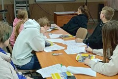 Wychowankowie oglądają film. Na stoliku znajdują się materiały potrzebne do zajęć.