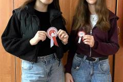 Dwie wychowanki stoją, w dłoniach trzymają kotyliony patriotyczne.