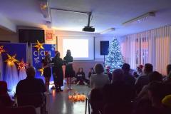 Na pierwszym planie widać śledzącą występ publiczność, dalej piękną świąteczną dekorację oraz występujących wychowanków 