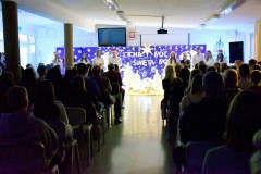 Na pierwszym planie widać siedzące osoby oglądające uroczystość. W tle stoi 10 osób: wychowankowie bursy. Ubrani odświętnie w biało – czarne stroje. Na głowie 5 osób znajdują się czapki Mikołaja. W rękach trzymają mikrofony i podkładki ze scenariuszami uroczystości. Wychowanka stojąca po lewej stronie trzyma w rękach saksofon. Za nimi znajduje się niebieska tablica na której znajdują się: wycięte z papieru białe gwiazdki, 2 białe anioły, lampki, 4 białe choinki. Pośrodku w drewnianym żłóbku leży postać Jezusa. Na tablicy znajduje się napis: Cicha noc, święta noc. Nad nim wisi biała duża gwiazda. Na podłodze znajduje się biała tkanina, na której leżą zapalone lampki.