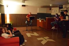 Wychowawca gra na gitarze, a wychowankowie zgromadzeni wokół, słuchają muzyki 