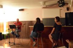 Wychowawca gra na gitarze, a wychowankowie zgromadzeni wokół, słuchają muzyki 