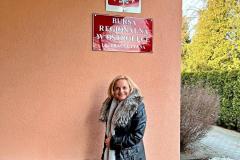 Pani Kurator pozuje do zdjęcia pod szyldem Bursy Regionalnej w Ostrołęce.