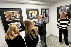 Grupa młodzieży z bursy zwiedza galerię sztuki, oglądając różnorodne prace w nowoczesnym, jasnym wnętrzu.
