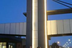 Dziesięcioro wychowanków stoi przed wejściem do Muzeum Żołnierzy Wyklętych w Ostrołęce. Za nimi znajduje się oświetlona kładka piesza, ulica oświetlona latarniami. Po lewej stronie stoją zaparkowane samochody. Na niebie zapada wieczór.