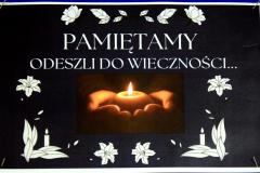 Na tablicy znajduje się napis: Pamiętamy – Odeszli do wieczności. Na tablicy znajdują się zdjęcia i opisy postaci zasłużonych dla polskiej, światowej kultury, nauki, sportu i sztuki. Do tablicy przypięte są kolorowe jesienne liście. 