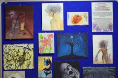 Tablica z pracami plastycznymi wychowanków bursy: kwiaty, przyroda, drzewo, twarze ludzi, martwa natura.