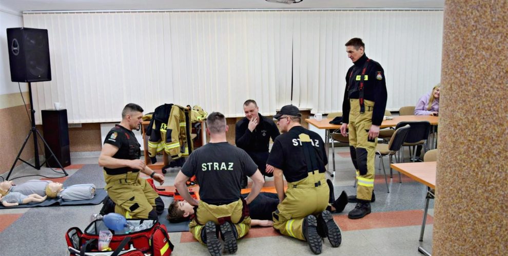 Druhowie z OSP prezentują jak prawidłowo i bezpiecznie przełożyć poszkodowanego na nosze