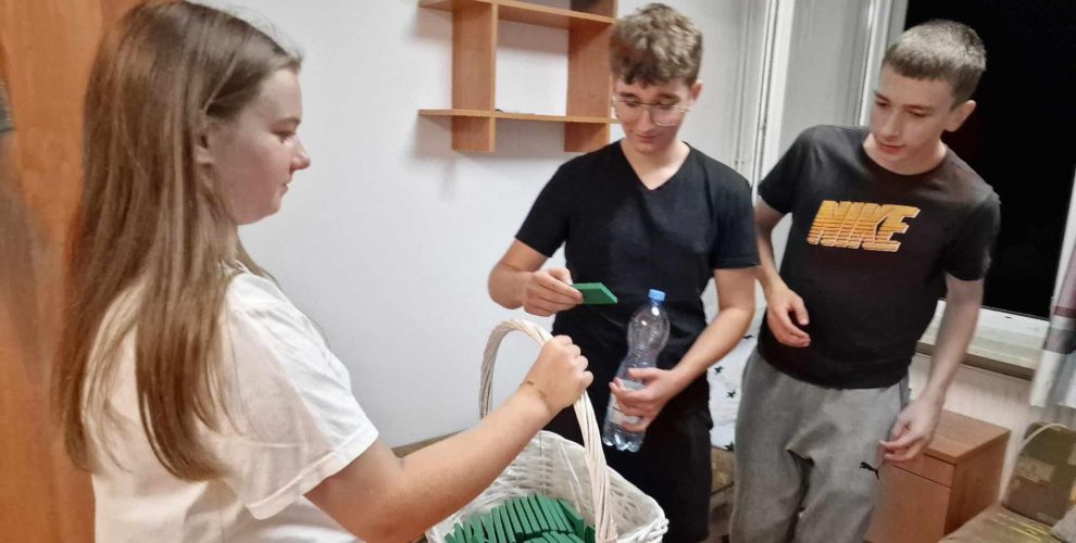 Zdjęcie przedstawia wychowankę częstującą chłopców czekoladkami
