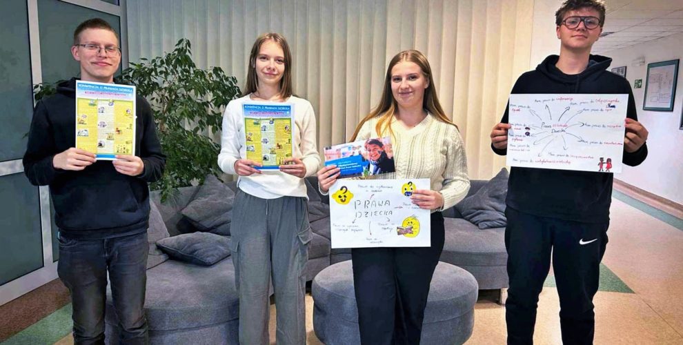 Grupa wychowanków prezentuje materiały, które wykorzystano podczas akcji informacyjnej. Plakaty powstały na zajęciach na temat praw dziecka.
